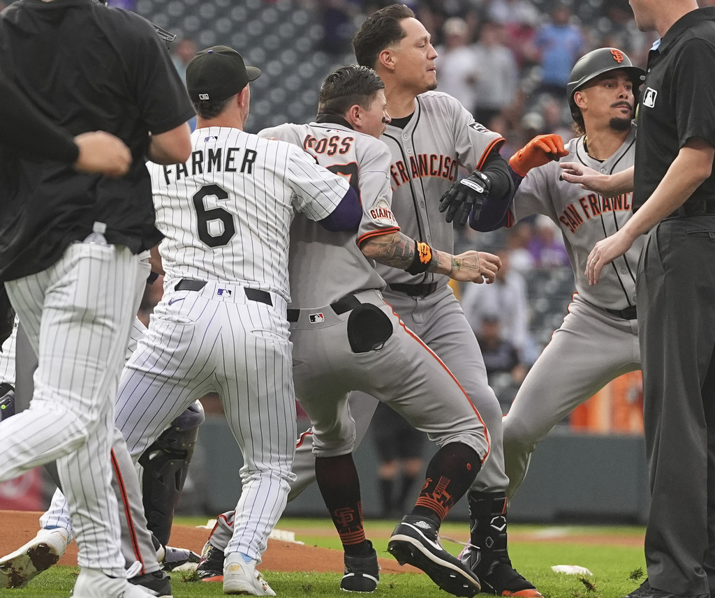 San Francisco Giants players pursue Colorado Rockies starting pitcher Kyle Freeland after he exchanged words with the Giants' Rafael Devers following Devers' two-run home run in the first inning of a baseball game Tuesday, Sept. 2, 2025, in Denver. (AP Photo/David Zalubowski)