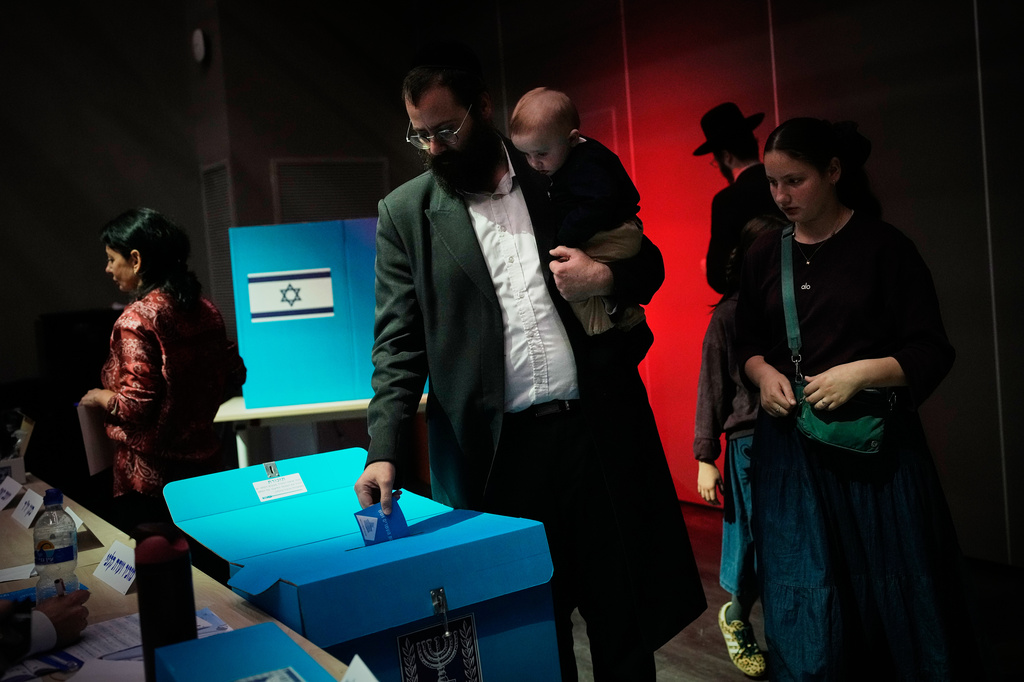 An ultra-Orthodox Jewish man holds his child as he casts his ballot at a school serving as a polling station during Israel's general election in Jerusalem, Tuesday, Oct. 27, 2026. (AP Photo/Ohad Zwigenberg)