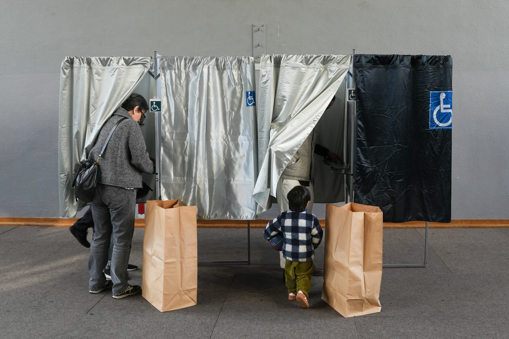 A man and his son stand in a voting booth during the second round of France's municipal elections in Paris, Sunday, March 22, 2026. (AP Photo/Thibault Camus)