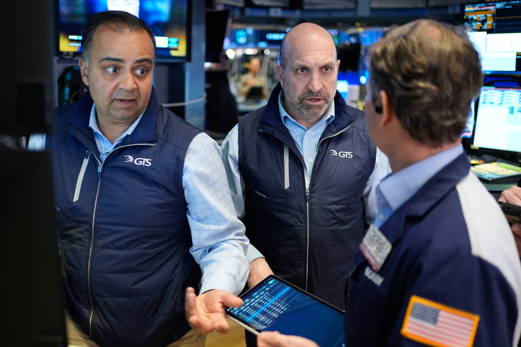 James Denaro, center, and Dilip Patel, left, work on the floor at the New York Stock Exchange in New York, Wednesday, March 25, 2026. (AP Photo/Seth Wenig)