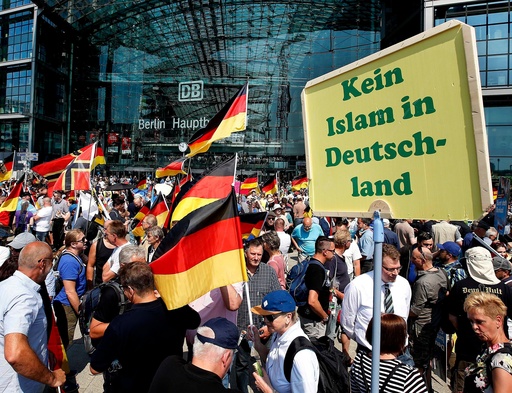 FILE - Supporters of the Alternative for Germany party wave flags in front of the train station in Berlin, May 27, 2018. The poster reads, "No Islam in Germany." (AP Photo/Michael Sohn, File) FILE - Supporters of the Alternative for Germany party wave flags in front of the train station in Berlin, May 27, 2018. The poster reads, "No Islam in Germany." (AP Photo/Michael Sohn, File)