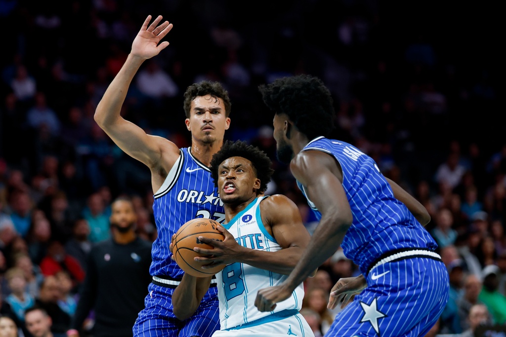 Charlotte Hornets guard Collin Sexton (8) drives to the basket between Orlando Magic forwards Tristan da Silva, left, and Jonathan Isaac, right, during the first half of an NBA basketball game in Charlotte, N.C., Thursday, Oct. 30, 2025. (AP Photo/Nell Redmond)