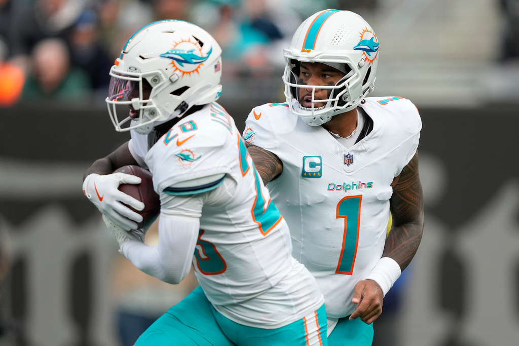 Miami Dolphins quarterback Tua Tagovailoa (1) hands off the ball to running back De'Von Achane (28) during the first quarter of an NFL football game, Sunday, Dec. 7, 2025, in East Rutherford, N.J. (AP Photo/Yuki Iwamura)