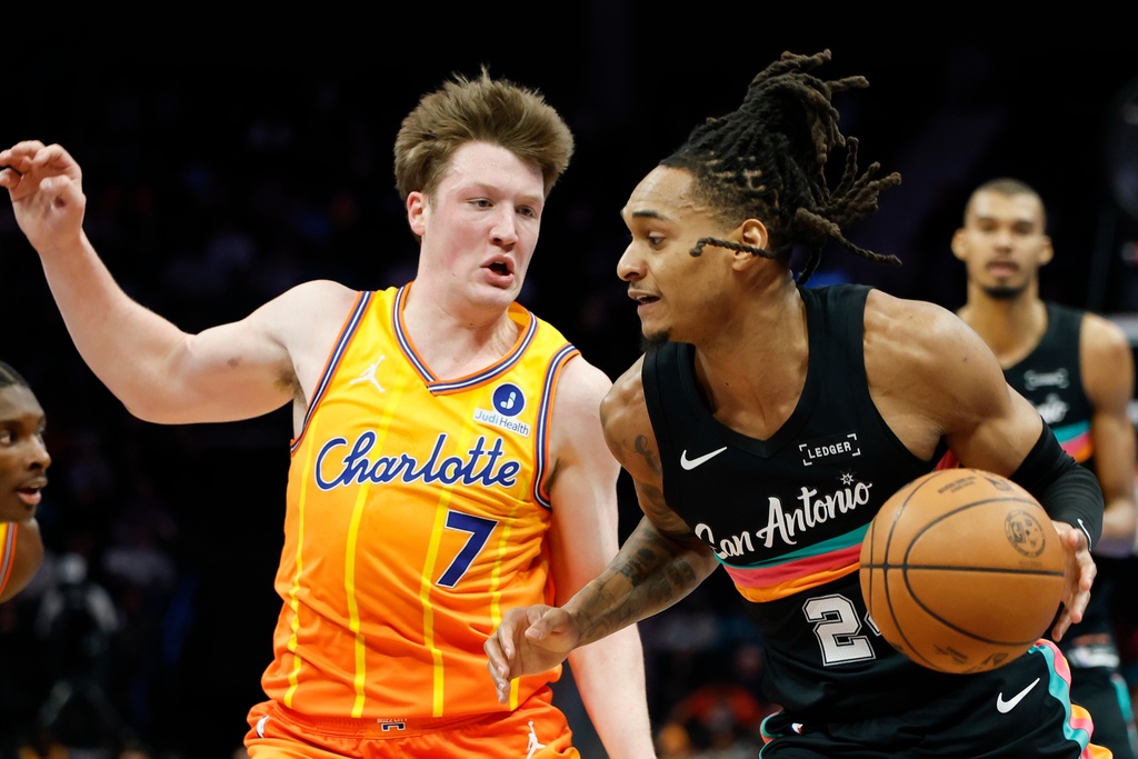 San Antonio Spurs guard Devin Vassell, right, drives to the basket against Charlotte Hornets guard Kon Knueppel (7) during the first half of an NBA basketball game in Charlotte, N.C., Saturday, Jan. 31, 2026. (AP Photo/Nell Redmond)