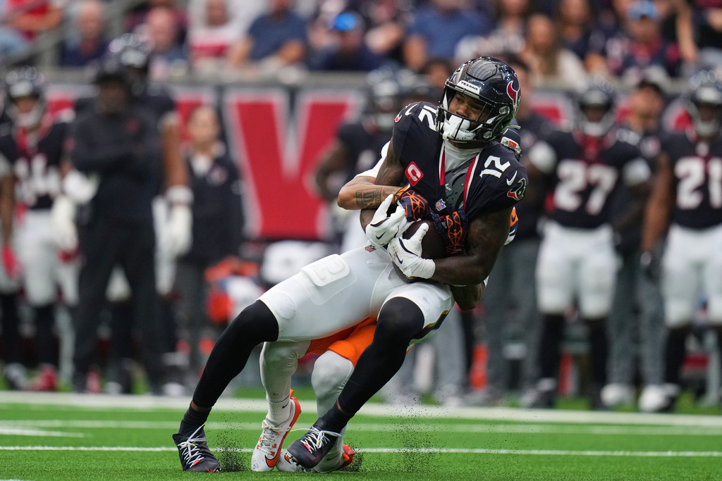 Houston Texans wide receiver Nico Collins (12) catches a pass and is stopped by Denver Broncos cornerback Kris Abrams-Draine, rear, in the first half of an NFL football game Sunday, Nov. 2, 2025, in Houston. (AP Photo/Eric Gay)