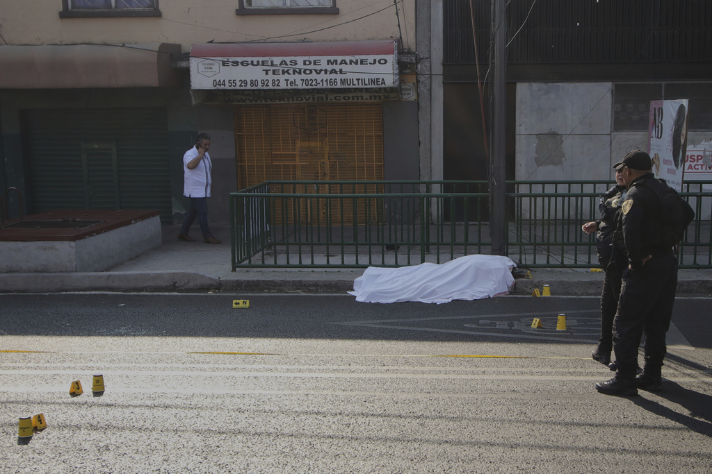 FILE - A body lies covered as police work at the site where the personal secretary and an advisor to Mexico City's mayor were killed by gunmen on a motorcycle, in Mexico City, May 20, 2025. (AP Photo/Tristan Velazquez, File)