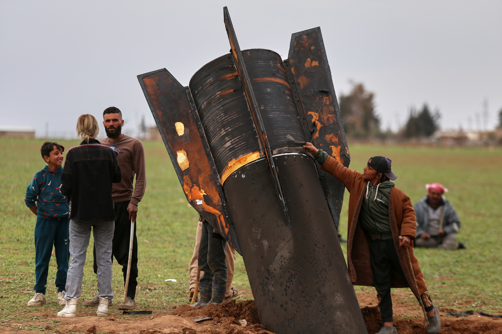FILE — Exposing himself to the danger of unexploded ordnance, a boy touches an unexploded Iranian projectile that landed in an open field in the outskirts of Qamishli, eastern Syria, March 4, 2026.(AP Photo/Baderkhan Ahmad, File)