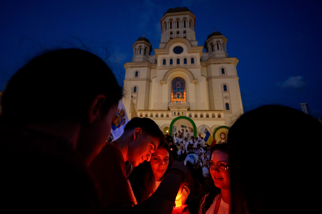 Youngsters light candles backdropped by the National Cathedral before the Procession of Lights, part of a four-day program of the International Meeting of Orthodox Youth (ITO), in Bucharest, Romania, Wednesday, Sept. 2, 2026. (AP Photo/Andreea Alexandru)
