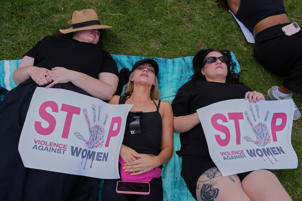 Participants lie on the ground holding signs that read "Stop violence against women" during a gender-based violence protest at the forecourt of the botanical gardens in Johannesburg, South Africa, Friday, Nov. 21, 2025. (Misper Apawu)