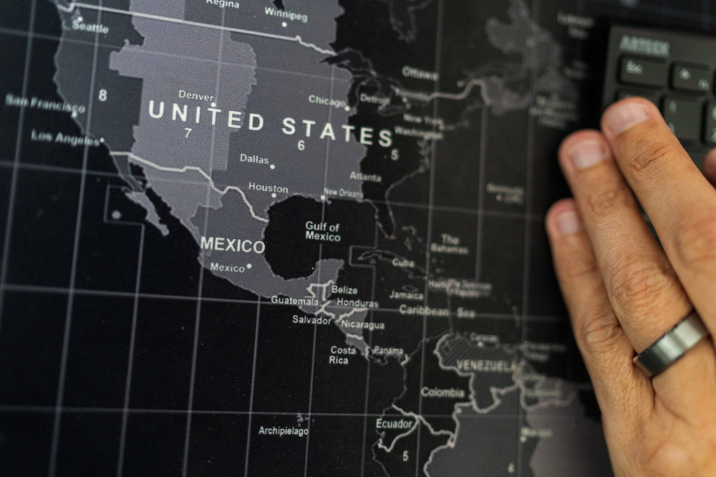 Alek Schott works on his computer next to a map showing the United States and Mexico at his home, Thursday, Oct. 16, 2025, in Houston. (AP Photo/David Goldman)