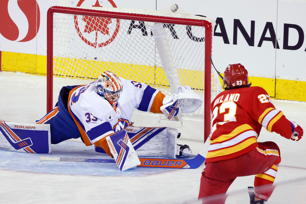 New York Islanders goalie David Rittich, left, is scored on by Calgary Flames' Justin Kirkland during second period NHL hockey action in Calgary, Alta., Saturday, Jan. 17, 2026. (Larry MacDougal/The Canadian Press via AP)