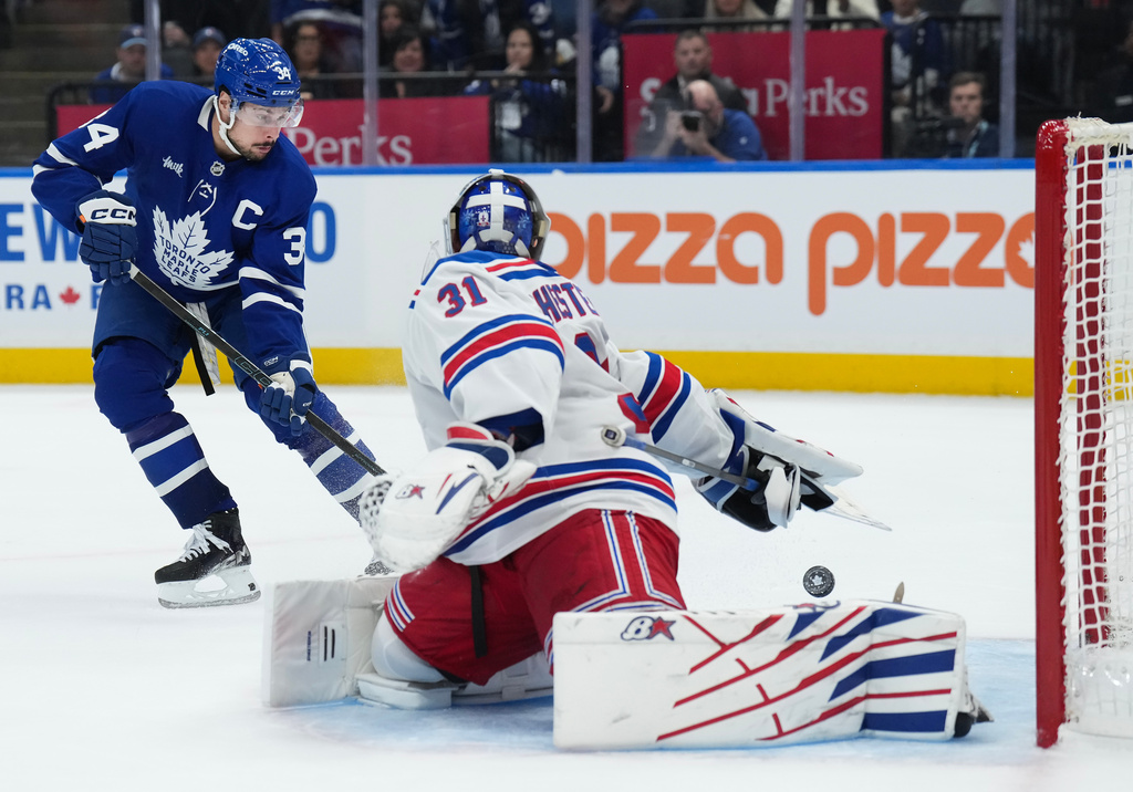 Toronto Maple Leafs' Auston Matthews (34) scores the winning goal past New York Rangers goaltender Igor Shesterkin (31) during overtime NHL hockey game action in Toronto, Thursday, Oct. 16, 2025. (Nathan Denette/The Canadian Press via AP)