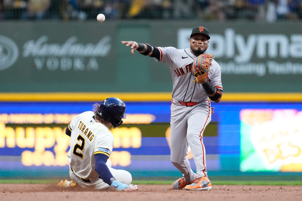 San Francisco Giants' Luis Arraez, right, throws to first base to turn a double play after tagging out Milwaukee Brewers' Brice Turang (2) at second during the fourth inning of a baseball game Monday, June 1, 2026, in Milwaukee. (AP Photo/Aaron Gash)