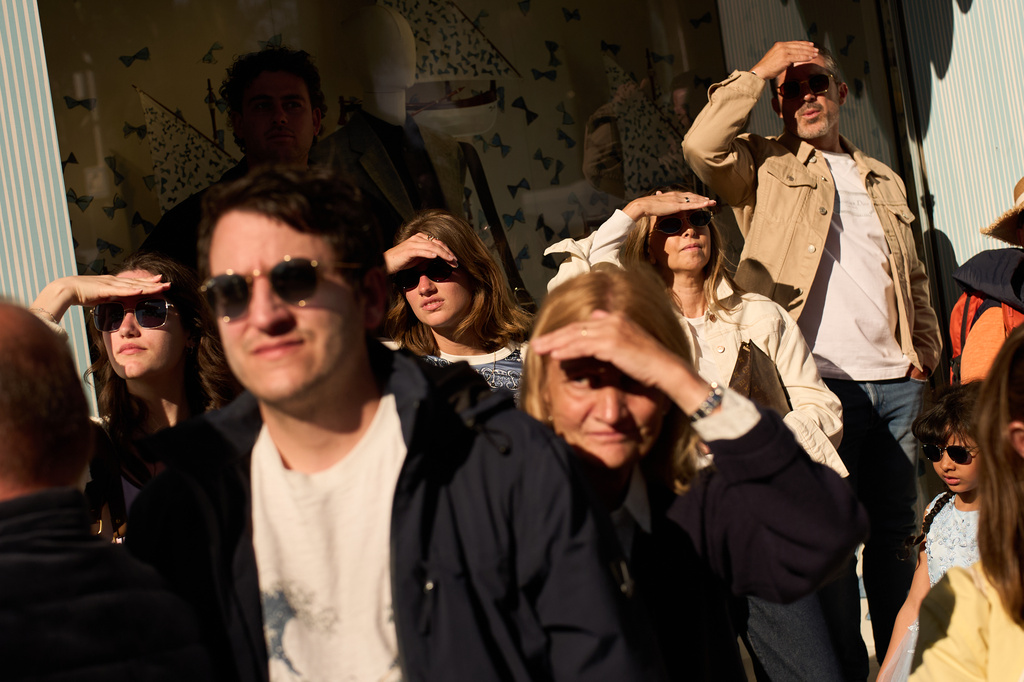 People shield their eyes from the sun while watching the red carpet during the 79th international film festival, Cannes, southern France, Friday, May 15, 2026. (AP Photo/John Locher)