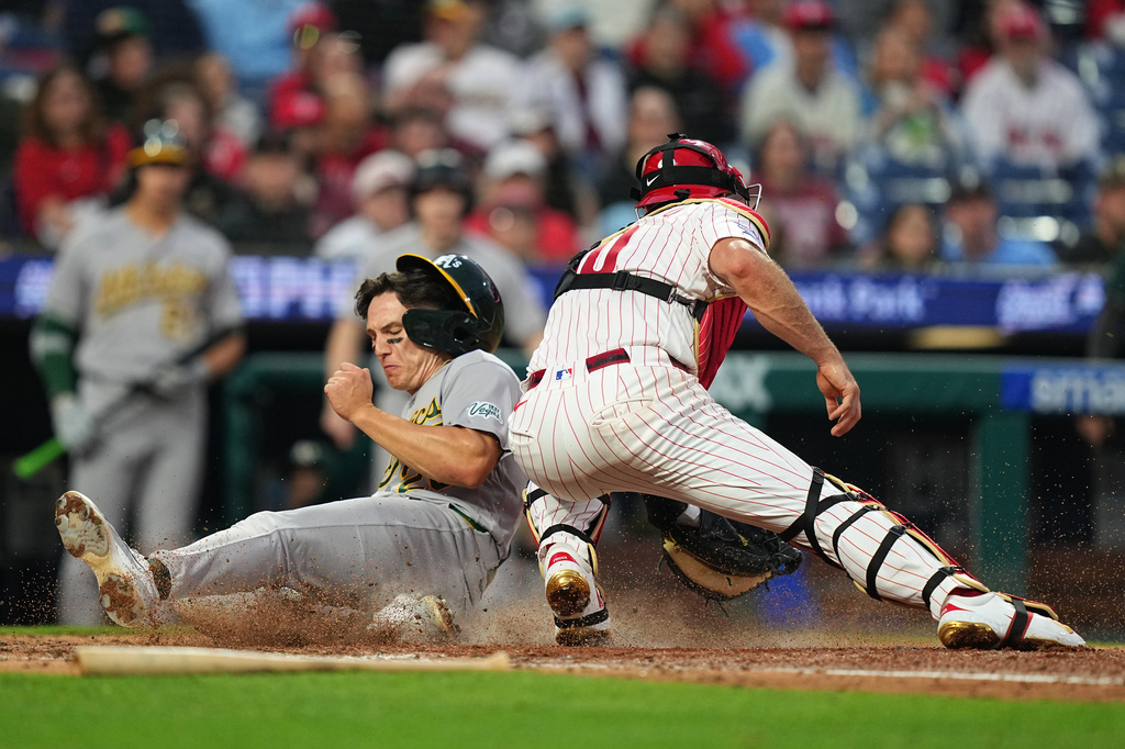 Athletics' Zack Gelof scores past Philadelphia Phillies catcher J.T. Realmuto during the fifth inning of a baseball game, Wednesday, May 6, 2026, in Philadelphia. (AP Photo/Matt Rourke)