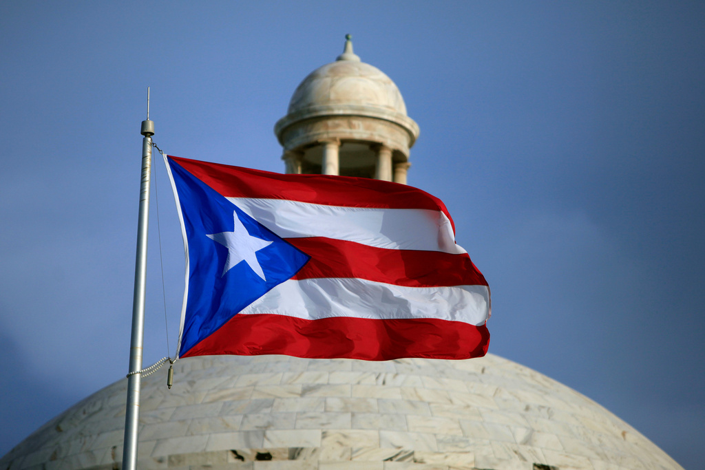 FILE - A Puerto Rican national flag flies in front of the Capitol building in San Juan, Puerto Rico, July 29, 2015. (AP Photo/Ricardo Arduengo, File)