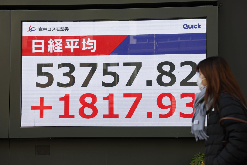 A person walks in front of an electronic stock board showing Japan's Nikkei index at a securities firm Tuesday, Jan. 13, 2026, in Tokyo. (Kyodo News via AP)