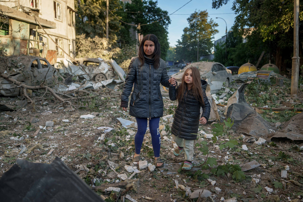 Olga Mudra, 35, and her daughter Natalia, 6, walk in the yard of their house damaged after a Russian strike on Kyiv, Ukraine, on Tuesday, June 2, 2026. (AP Photo/Evgeniy Maloletka)