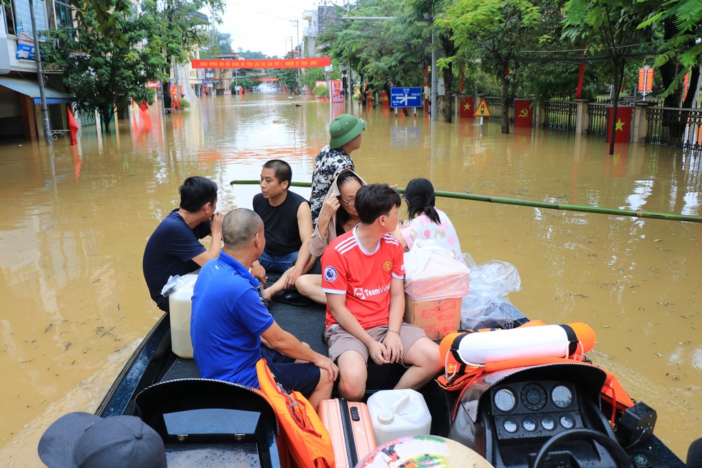 People move by a boat in a flooded street caused by rain following typhoon Bualoi in Lao Cai, Vietnam, Tuesday, Sept. 30, 2025. (Do Tuan Anh/VNA via AP)
