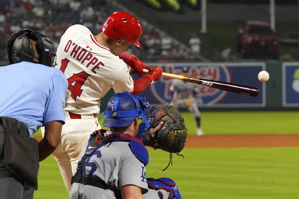 Los Angeles Angels' Logan O'Hoppe, center, hits an RBI single as Los Angeles Dodgers catcher Will Smith watches during the eighth inning of a baseball game Wednesday, Aug. 13, 2025, in Anaheim, Calif. (AP Photo/Mark J. Terrill)