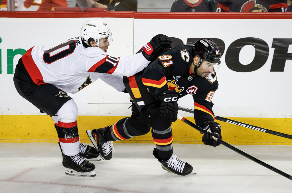 Ottawa Senators' Jordan Spence, left, checks Calgary Flames' Nazem Kadri during the third period of an NHL hockey game in Calgary, Alberta, Thursday, March 5, 2026. (Jeff McIntosh/The Canadian Press via AP)