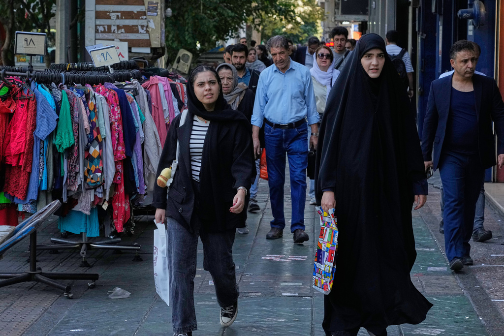 People walk on a sidewalk at the Enqelab-e-Eslami (Islamic Revolution) street, in Tehran, Iran, Saturday, Sept. 27, 2025. (AP Photo/Vahid Salemi)