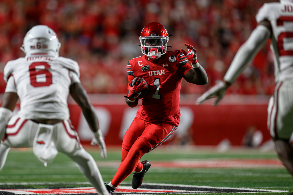 Utah running back Wayshawn Parker (1) runs the ball as Arkansas linebacker Phoenix Jackson (8) during the first half of an NCAA college football game Saturday, Sept. 12, 2026, in Salt Lake City. (AP Photo/Tyler Tate)