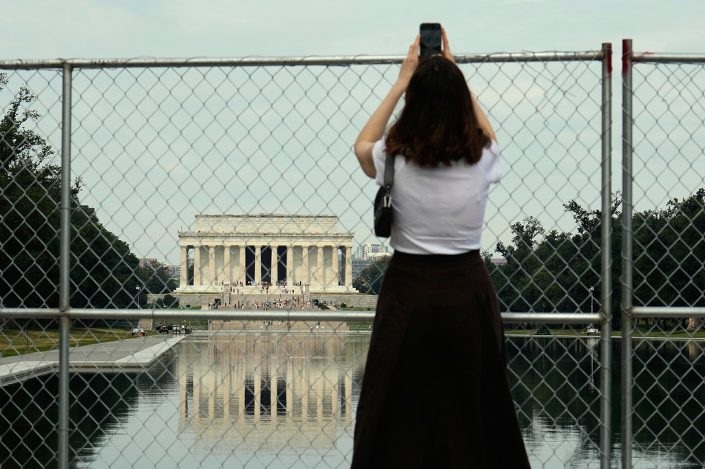 A person holds a cell phone high to take a photo of the Lincoln Memorial Reflecting Pool and the Lincoln Memorial from behind a chain link fence Friday, June 26, 2026, in Washington. (AP Photo/Carolyn Kaster)