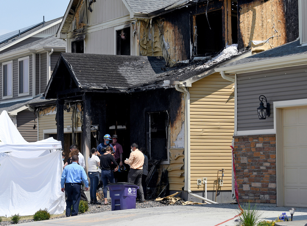 FILE - Investigators stand outside a house where five immigrants from Senegal were found dead after a fire in suburban Denver on Aug. 5, 2020. (AP Photo/Thomas Peipert, File)
