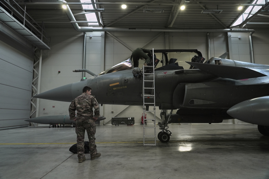 A flight-crew member climbs into the cockpit of a French air force Rafale fighter jet stationed on a NATO air-policing mission at the Siauliai Air Base in Lithuania as another member of the French detachment stands at the foot of the ladder on Sunday, April 19, 2026 (AP Photo/John Leicester)