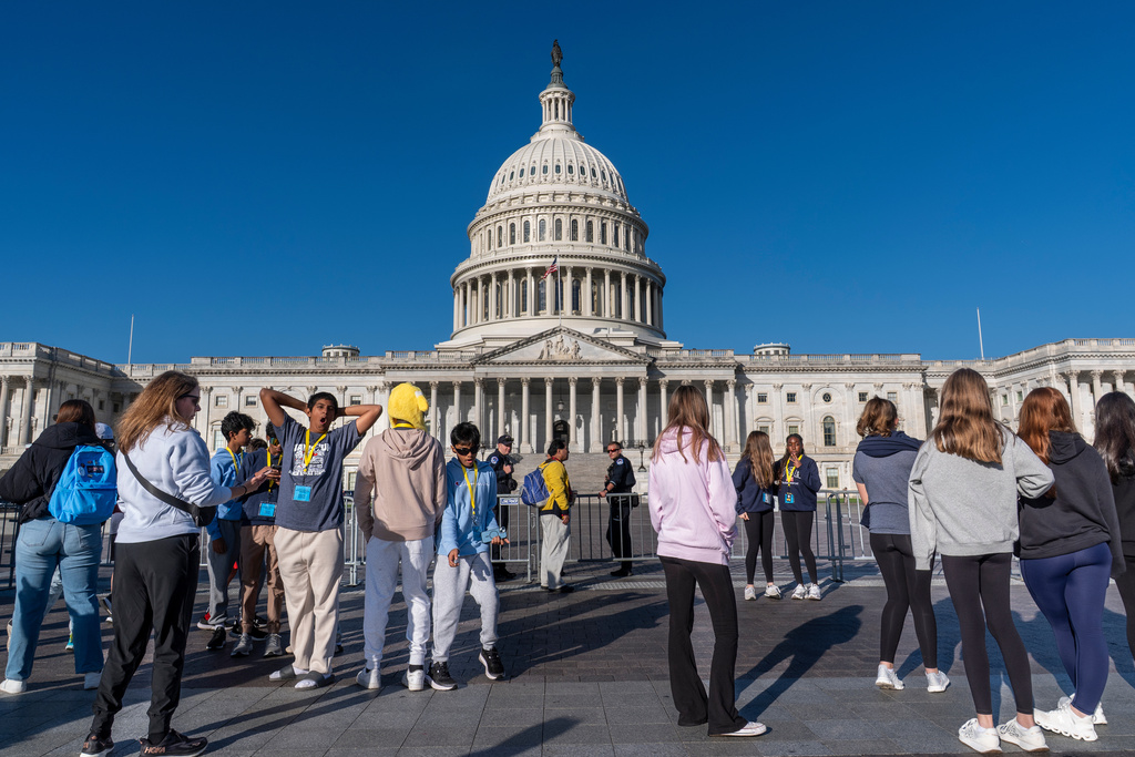 Students from Columbus, Ohio, wait outside a barrier as U.S. Capitol Police watch over the East Plaza where congressional leaders will have a news conferences on the government shutdown at the Capitol in Washington, Wednesday, Oct. 15, 2025. (AP Photo/J. Scott Applewhite)