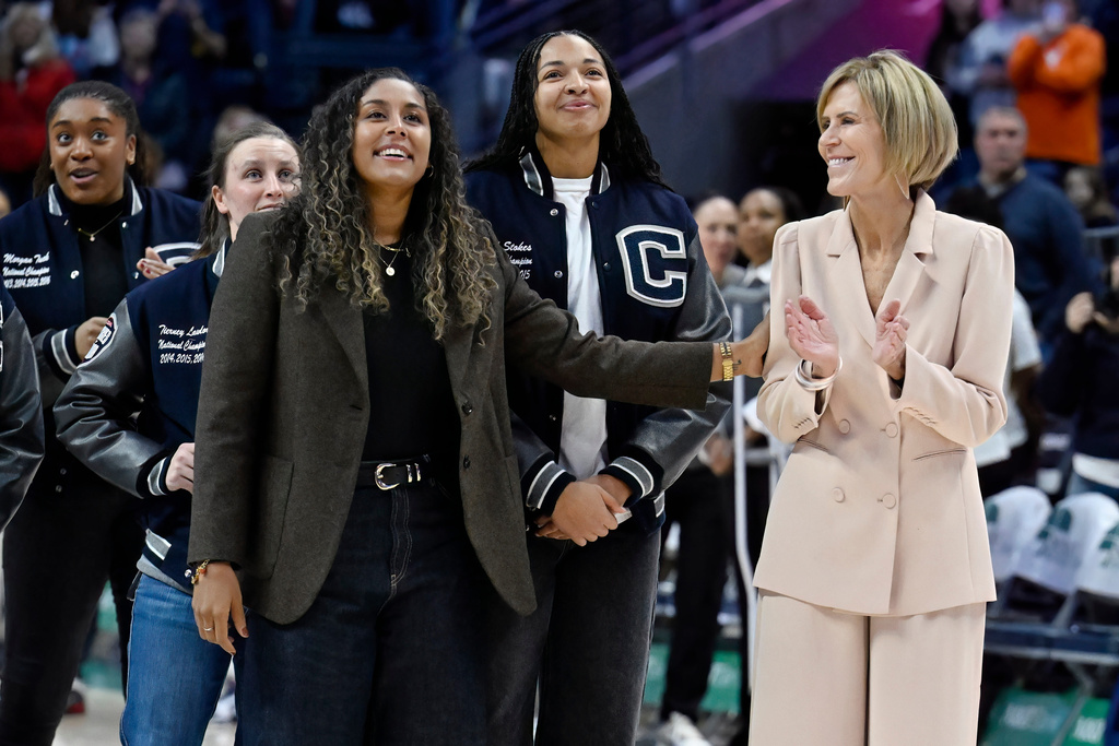 Former UConn player Kaleena Mosqueda-Lewis reaches for associate head coach Chris Dailey while surrounded by former teammates during a pregame ceremony honoring the UConn 2015 and 2016 championship basketball teams before an NCAA college basketball game, Thursday, Jan. 15, 2026, in Storrs, Conn. (AP Photo/Jessica Hill)