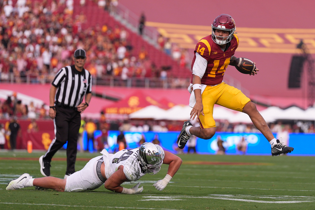 Southern California quarterback Jayden Maiava, right, jumps away from Oregon linebacker Teitum Tuioti during the first half of an NCAA college football game, Saturday, Sept. 26, 2026, in Los Angeles. (AP Photo/Mark J. Terrill)