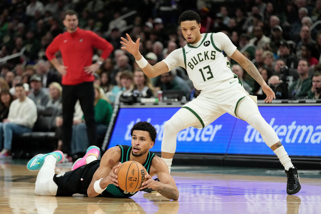 Portland Trail Blazers' Toumani Camara looks to pass from the floor against Milwaukee Bucks' Ryan Rollins (13) during the first half of an NBA basketball game Monday, Nov. 24, 2025, in Milwaukee. (AP Photo/Aaron Gash)