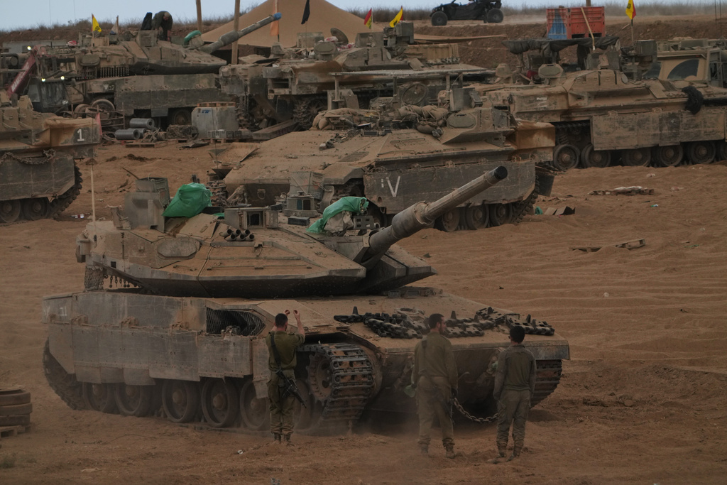 Israeli soldiers work on a tank near the Israeli-Gaza border, as seen from southern Israel, Thursday, Oct. 9, 2025, following the announcement that Israel and Hamas have agreed to the first phase of a peace plan to pause the fighting. (AP Photo/Ariel Schalit)