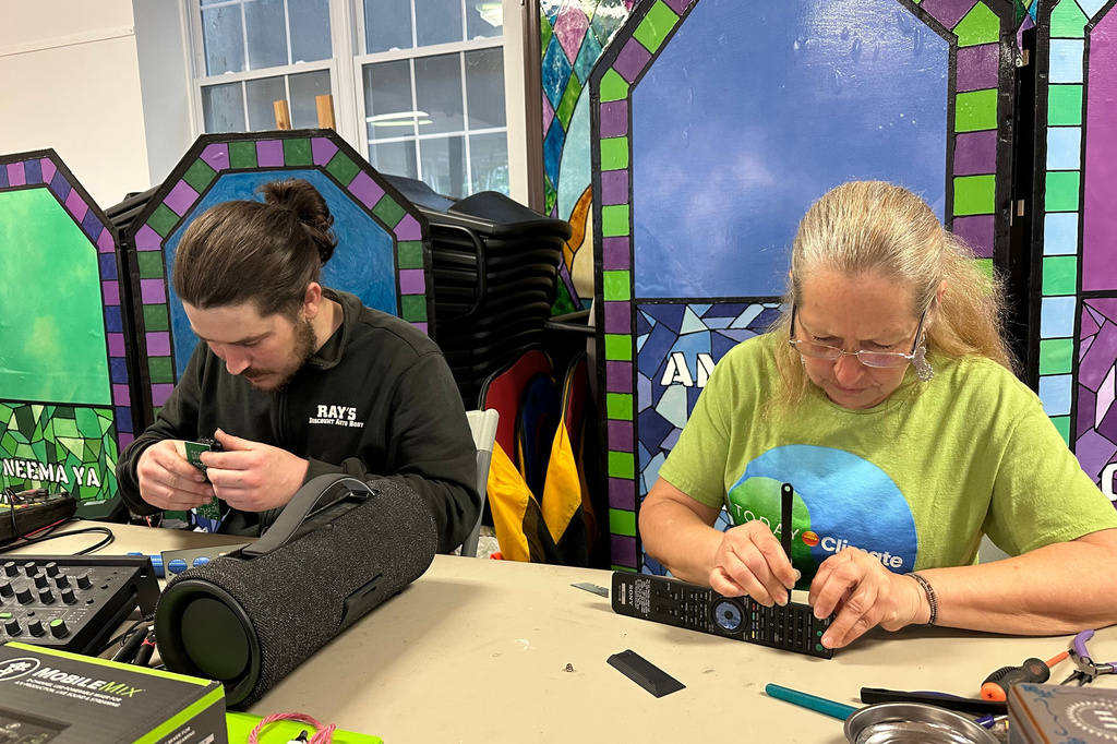 Electronic repair coach Dan Casey and his mother Diane Casey work on a sound-mixing device at a Repair Café in New Paltz, N.Y., May 23, 2026. (AP Photo/Michael Weissenstein)