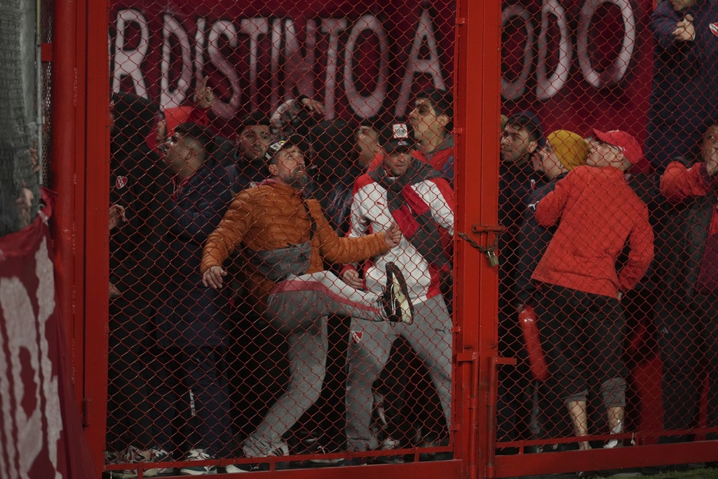 Fans of Argentina's Independiente bang on a barrier during a Copa Sudamericana round of sixteen second leg soccer match against Universidad de Chile at the Libertadores de America stadium in Avellaneda, Argentina, Wednesday, Aug. 20, 2025. (AP Photo/Gustavo Garello)