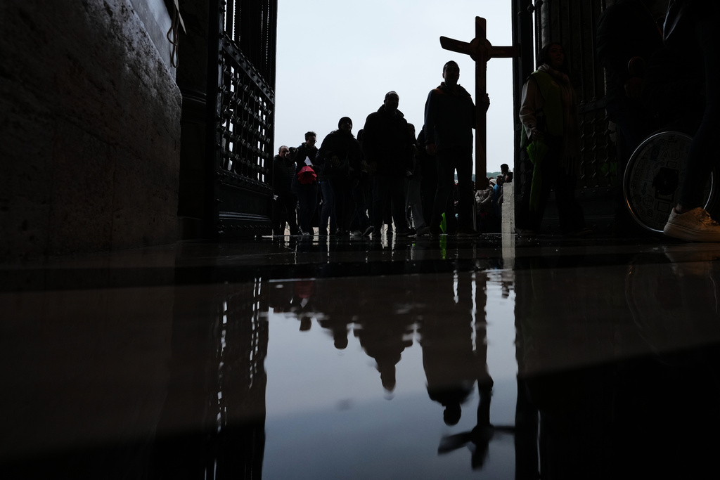 Pilgrims and faithful hold a crucifix as they arrive to St. Peter's Basilica at the Vatican to cross the Holy Door on the last day of its public opening, Monday, Jan. 5, 2026. (AP Photo/Alessandra Tarantino)