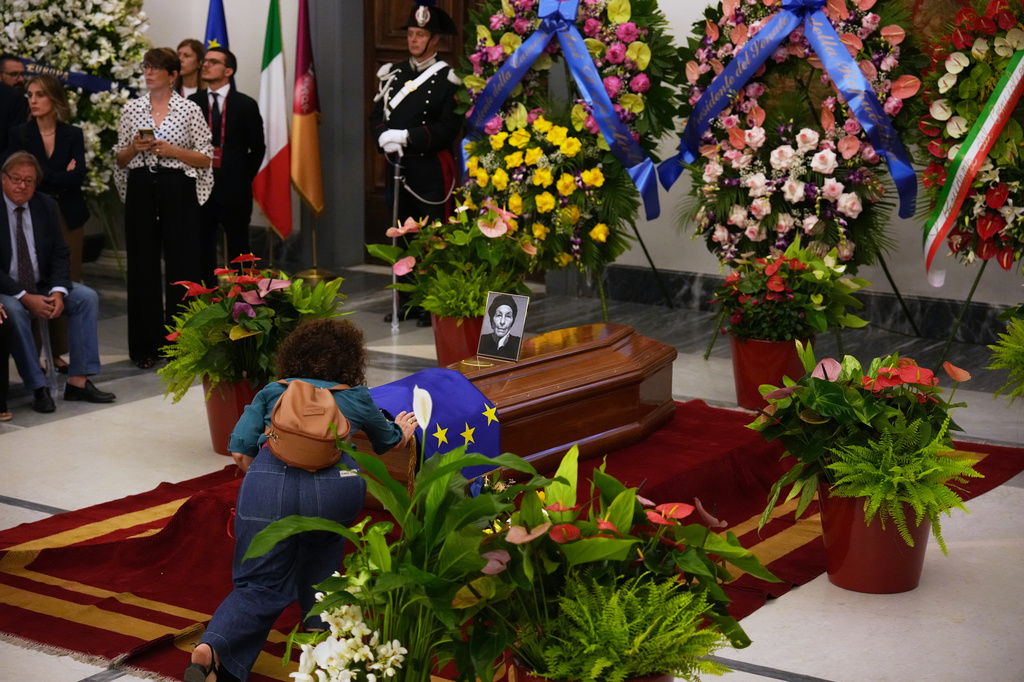 A woman touches the casket of Emma Bonino, who rose to political prominence in the 1970s campaigning to legalize abortion in heavily Roman Catholic Italy, during her lying in state in Rome's City Hall, Sunday, Sept. 13, 2026. (AP Photo/Andrew Medichini)