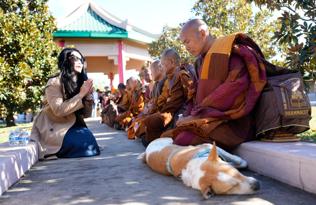 Buddhist monk Panna Kara with dog named Aloka, along with other monks from the Huong Dao Vipassana Bhavana Center in Fort Worth, who are undertaking a 2,300 mile pilgrimage of "Walk for Peace," rest after arriving to a welcome ceremony at Hong Kong City Mall in Houston, Friday, Nov. 14, 2025. (Melissa Phillip/Houston Chronicle via AP)