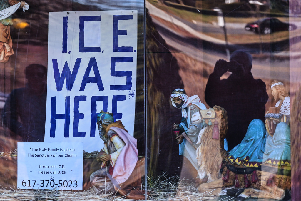 An "ICE WAS HERE" sign is posted in the spot for the baby Jesus at a nativity display at St. Susanna Church, Tuesday, Dec. 9, 2025, in Dedham, Mass. (AP Photo/Charles Krupa)