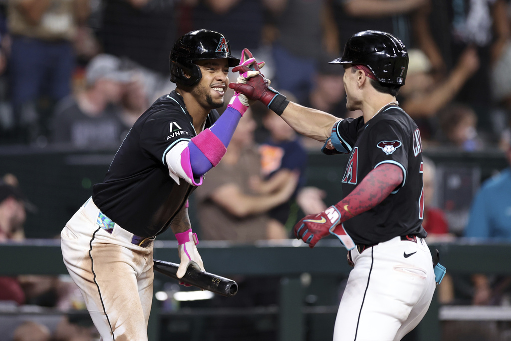 Arizona Diamondbacks' Corbin Carroll, right, high-fives Ketel Marte, left, after hitting a two-run home run against the Colorado Rockies during the fifth inning of a baseball game Saturday, Aug. 9, 2025, in Phoenix. (AP Photo/Chris Coduto)