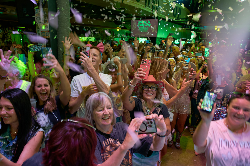 People celebrate at a bar on Broadway as the song "9 to 5" is performed during a Dolly Parton Day event honoring the late country music artist, Friday, Sept. 25, 2026, in Nashville, Tenn. (AP Photo/George Walker IV)