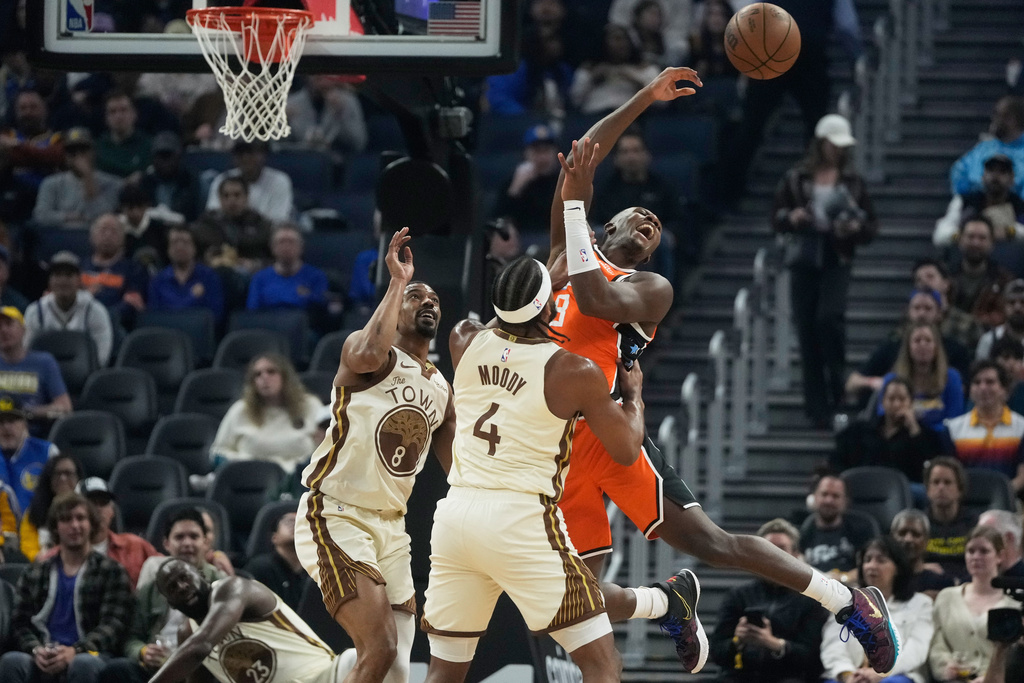 Los Angeles Clippers guard Kris Dunn, right, passes the ball while being defended by Golden State Warriors guard De'Anthony Melton, left, and guard Moses Moody (4) during the first half of an NBA basketball game in San Francisco, Monday, March 2, 2026. (AP Photo/Jeff Chiu)