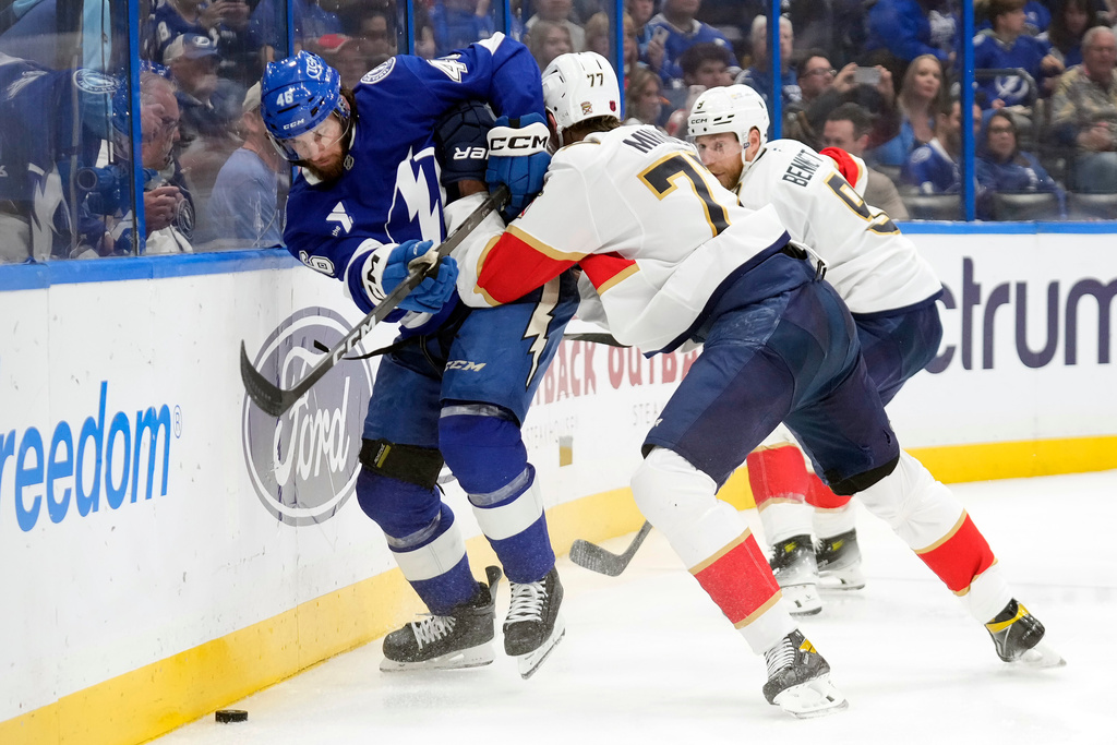 Florida Panthers defenseman Niko Mikkola (77) pins Tampa Bay Lightning right wing Scott Sabourin (46) to the dasher as he chases the puck during the second period of an NHL hockey game Monday, Dec. 15, 2025, in Tampa, Fla. (AP Photo/Chris O'Meara)