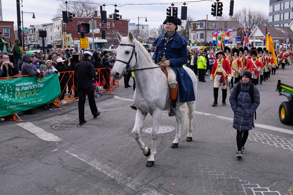 A rider portraying Paul Revere is followed by re-enactors marching as Revolutionary War British soldiers in red coats during the annual St. Patrick's Day parade through the South Boston neighborhood, Sunday, March 15, 2026, in Boston. (AP Photo/Charles Krupa)