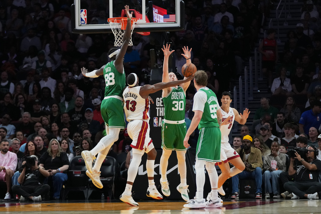Boston Celtics forward Sam Hauser (30) blocks a shot by Miami Heat center Bam Adebayo (13) during the first half of an NBA basketball game, Wednesday, April 1, 2026, in Miami. (AP Photo/Lynne Sladky)