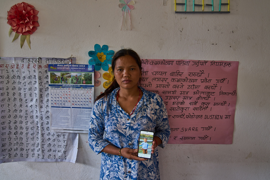 Pasang Maya Tamang stands inside a classroom converted into a temporary shelter as she shows a photograph of her 5-year-old son, who was swept away by flash floods, in Nepal's Nuwakot district, Tuesday, Sept. 8, 2026. (AP Photo/Dar Yasin)