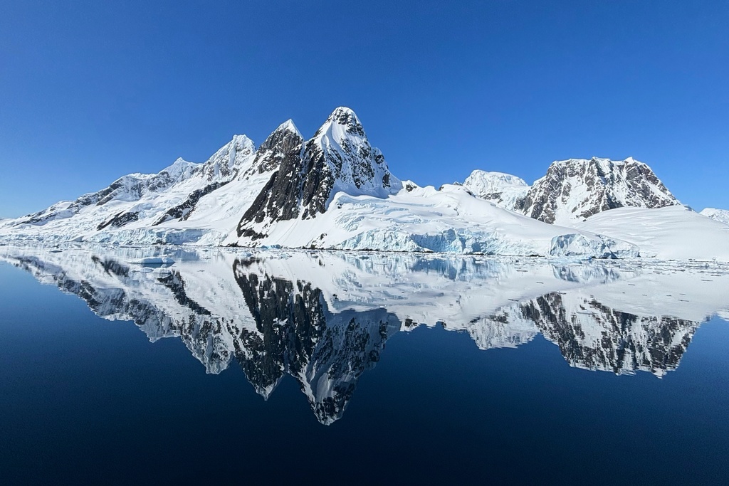An ice covered rock formation is reflected in the waters at Pleneau Island in Antarctica, Monday, Nov. 24, 2025. (AP Photo/Mark Baker)