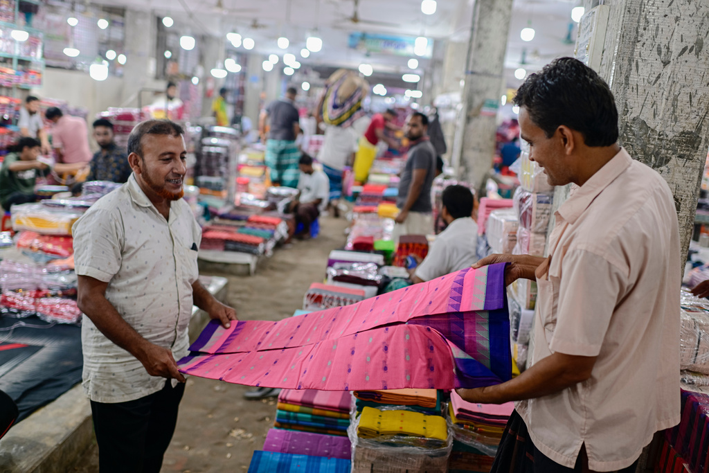 A customer examines a Tangail sari at a weekly wholesale market in Tangail District, Bangladesh, Nov. 5, 2025. (AP Photo/Mahmud Hossain Opu)